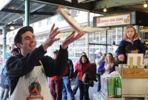 Workers at Pike Place Fish Market in Seattle throwing fish and engaging with customers, showing a fun workplace culture built on an attitude of gratitude.