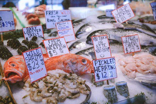 Workers at Pike Place Fish Market in Seattle throwing fish and engaging with customers, showing a fun workplace culture built on an attitude of gratitude.